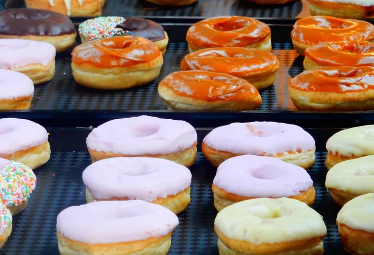 Rows of frosted donuts in a bakery case