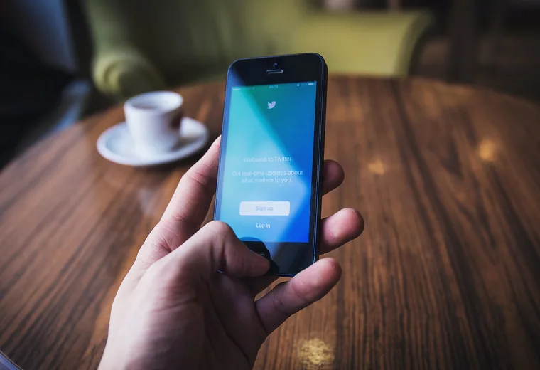 A smartphone next to a cup of coffee